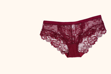 Beautiful lace lingerie on a beige isolated background. Burgundy underpants classic. Elegant underwear.