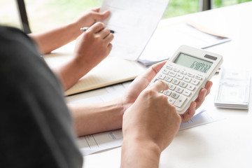 couple working saving account book and calculating her monthly expenses on calculator to calculate financial data, filling in individual income tax return.