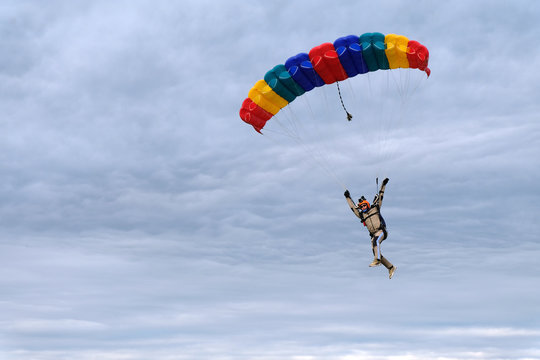 Skydiving. A skydiver is piloting a rainbow canopy.