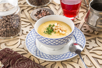 vegetable soup with pumpkin and croutons and glass of red drink on oriental wooden table