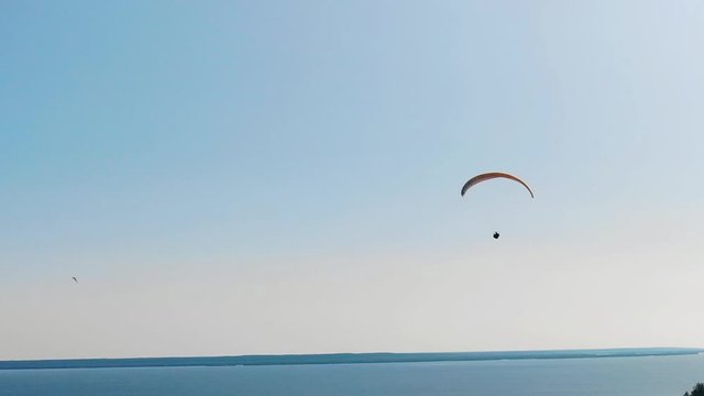 A man with a paraplane on a clear sky background.