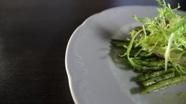 Blanched asparagus and grilled fillet of pike perch, served with lemon and herbs on a white plate