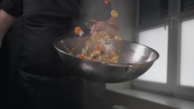 Chef tosses fried vegetables with noodles in hot wok in slow motion, cooking asian noodles, stirring in a hot pan, chinese fast food restaurant, slow mo cooking, Full HD Prores HQ 10 bit in 240 fps