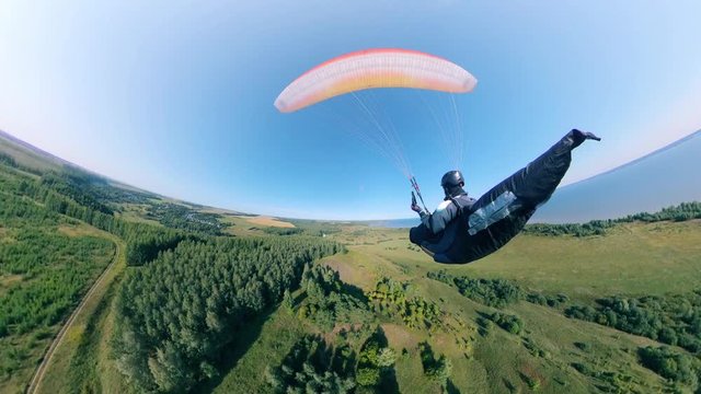 A man in helmet flying with paraplane over field.