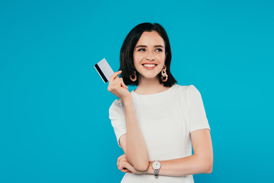 smiling elegant woman in dress holding credit card isolated on blue
