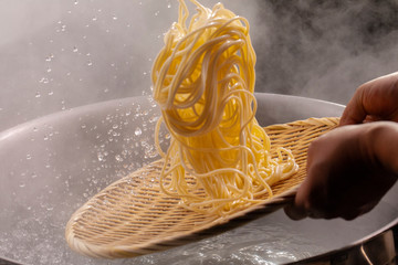The bamboo pole picks up the hot noodles in the cauldron, and the noodle teeth have an appetite