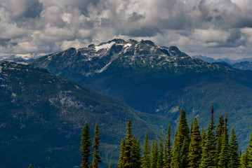 Alpine mountain range, located in British Columbia, Canada, in the summer.  There is a small amount of snow on the top of the mountain. 