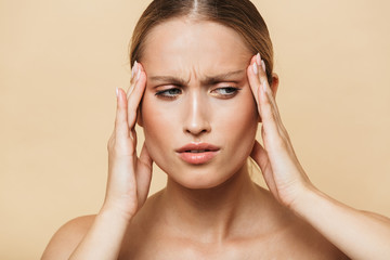 Image of sad half-naked woman rubbing her temples and looking aside