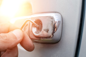 Car thief. Close - up of a man's hands opening the car with a lock pick. Photo with illumination,...