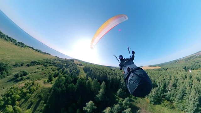 Athlete training with paraglider, flying over fields.