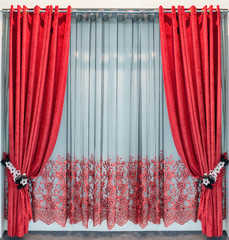 Red velvet curtains with eyelets on a round metal cornice, tie-backs from lace flowers and the...