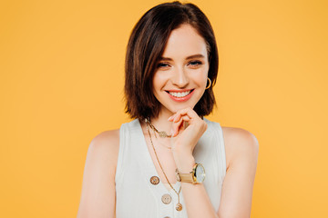 smiling elegant girl with hand on chin isolated on yellow