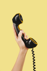 Hand of person holding black telephone receiver - obrazy, fototapety, plakaty
