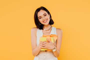happy smiling girl holding gift box isolated on yellow