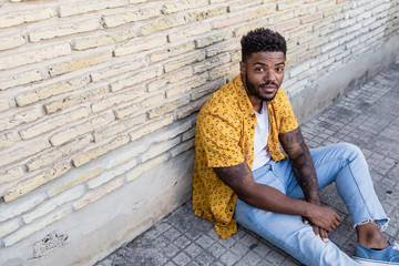 Portrait of a handsome young american man sitting on a brick wall