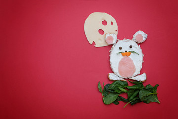 Creative edible christmas rat, mouse food art. Food for kids and festive table. Rat made from bread with cream cheeseon red background.