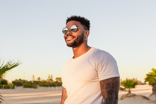Portrait of a handsome american man smiling on the beach at sunset