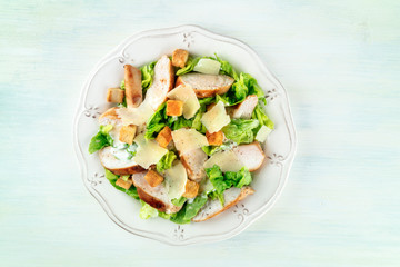 Chicken Caesar salad. Slices of chicken breast, green lettuce, Parmesan cheese, and croutons, shot from the top