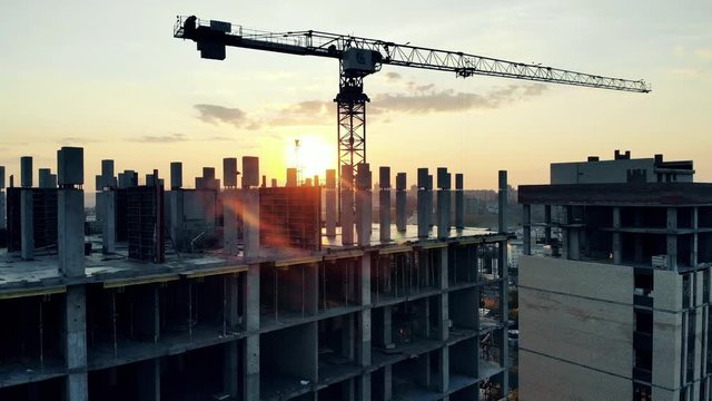 Sunset construction site with a multistory house and a crane