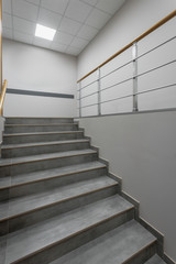 Background of gray staircase with wooden handrail in office building