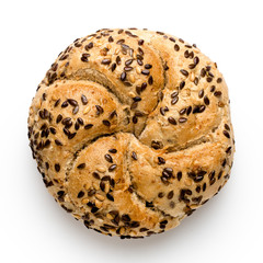 Traditional whole wheat kaiser roll with linseeds and sesame seeds isolated on white. Top view.
