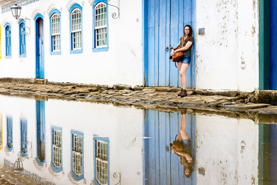 Beautiful model standing at blue wooden door in the historic city of Paraty, Rio de Janeiro, Brazil.