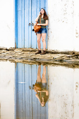 Beautiful model standing over blue wooden door talking on the phone in the historic city of Paraty, Rio de Janeiro, Brazil.