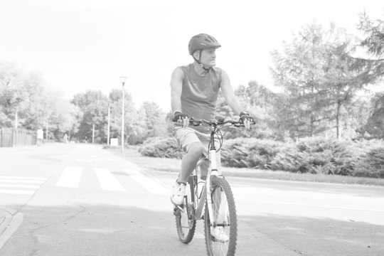 Black and white photo of Determined senior man riding bicycle in park