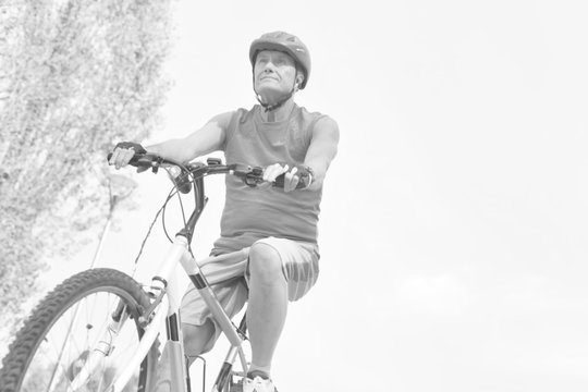 Black and white photo of Determined senior man riding bicycle in park