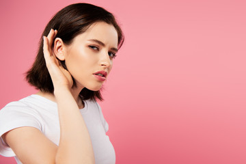 beautiful focused girl listening isolated on pink