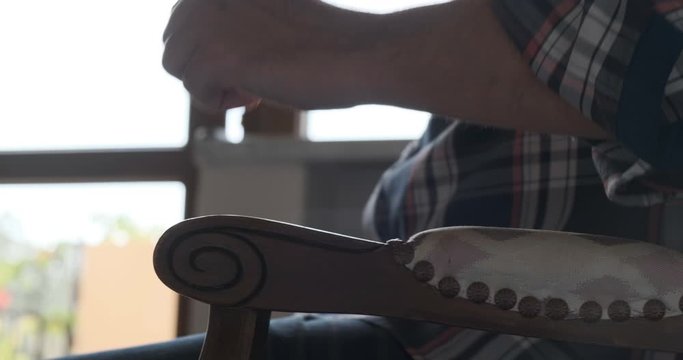 Anxious, impatient man sitting down in a chair, pounding on the chair arm and getting up fast, while wearing casual clothing, at home.