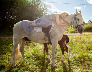 Naklejka na ściany i meble Beautiful caucasian young girl walking with a horse and enjoys summertime in countryside.