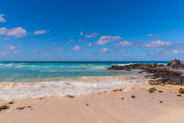 Tropical sandy beach with blue water and blue sky