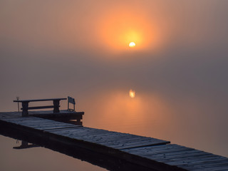 Fantastic foggy lake in the sunlight, completely blurred background, fog picture, fisherman's footbridge in the foreground