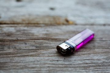 Close up of a pink lighter on a wooden background.