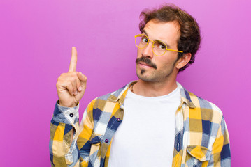 young handsome man feeling like a genius holding finger proudly up in the air after realizing a...