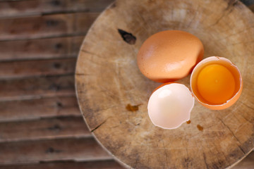 Brown eggs on a wooden chopping board There is a yolk in the egg shell. The brown egg has a drop of water because it is removing from the refrigerator.