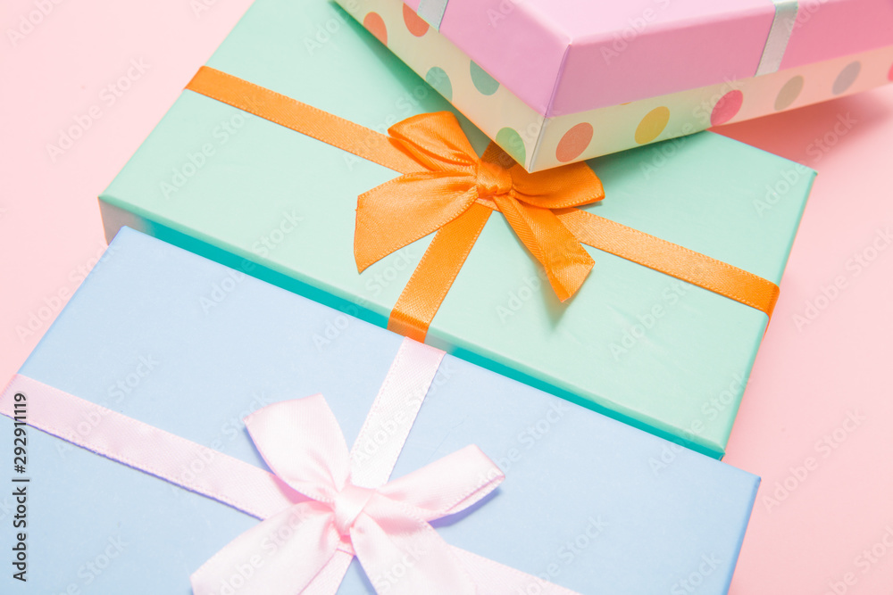 Poster multi-colored boxes with bows on a pink background