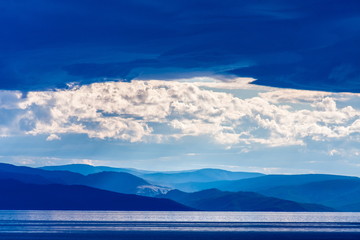 Storm with heavy rain and bright sun over the shore of lake Baikal