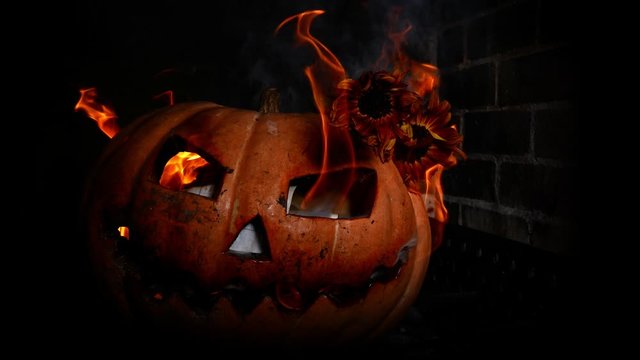 Carved terrible pumpkin, in hellfire. A crazy face from the eyes burns fire. Halloween pumpkin.
