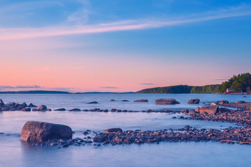 Langzeitbelichtung des Sonnenuntergangs am Paijanne-See. Schöne Landschaft mit Steinstrand, Pinienwald und Wasser. See Paijanne, Finnland. © Della_Liner