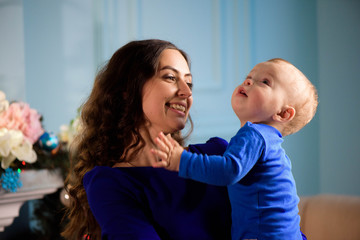 Toddler with mom in the festively decorated room with Christmas tree.