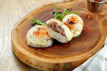 Baked kebab in onion ring with cheese and spices on a wooden board. Restaurant style street food.