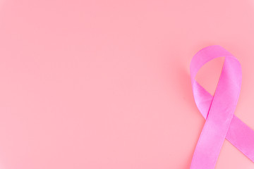 Pink ribbon breast cancer on pink background with copy space for text. Flat lay, top view.