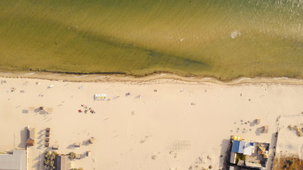 Sandy beach with sunbathing tourists, view from drone. Aerial view of beach with tourists swimming in clear sea water.