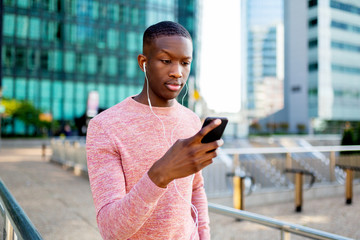 young black man listening to music with headphones and phone in the city