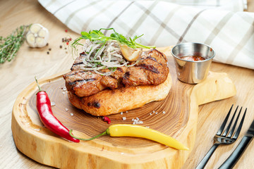 Close up on tasty Grilled Pork neck served on pita bread with onion, microgreen and hot pepper. Wooden background. Copy space. Selective focus