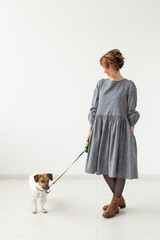 Fashion and pet's owner concept - young woman posing in clothes with jack russell at studio on white background