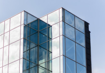 windows of a tall office building of a skyscraper without people with reflection of sky and clouds