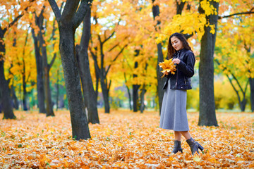 woman posing with autumn leaves in city park, outdoor portrait